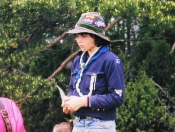 Boy standing outside on the grass dressed in sea scout attire